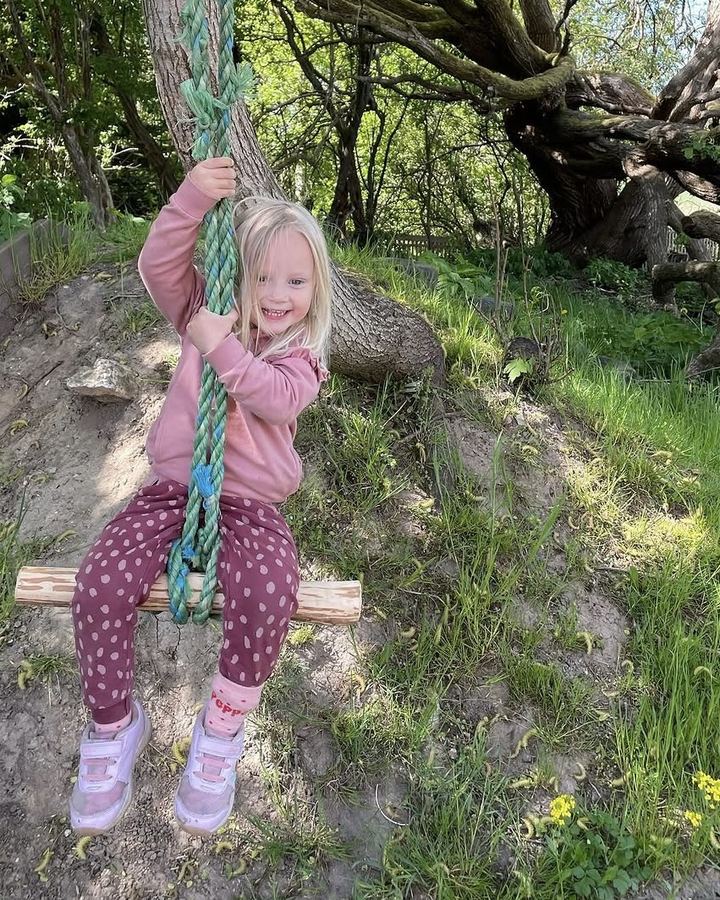 Pige på gyngen i skrænten bag haven