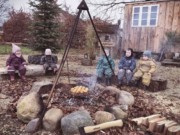 Børn samlet omkring bålpladsen i haven